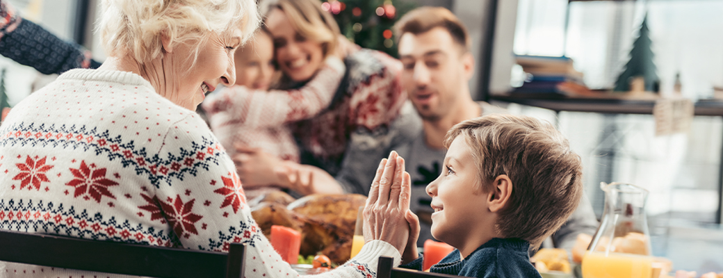 Image of grandmother high-fiving grandson at dinner table